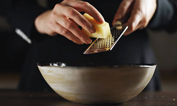 istock Woman grating cheese on a grater in a kitchen. 2211787724