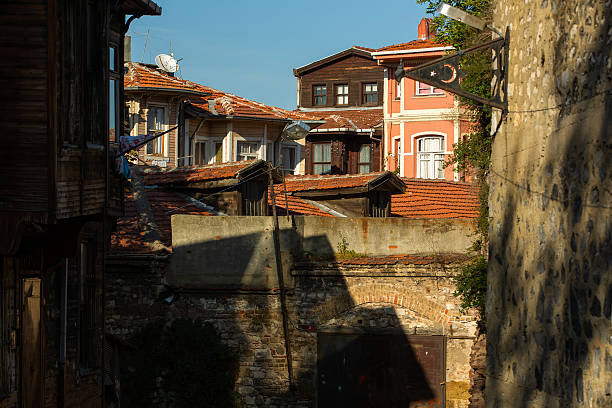 Istanbul, Turkey – November 22, 2015: View of the roofs and walls of old buildings. In the background, damaged roofs and colorful houses are visible. Sunlight casts shadows on the walls of the buildings, creating a play of light and shade between the structures.