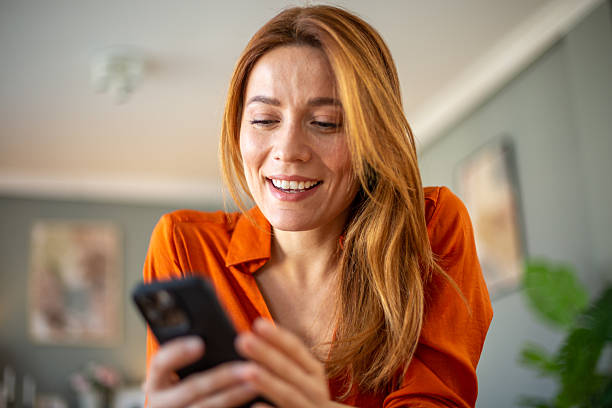istock Smiling woman using smartphone at home reading good news 2211788143