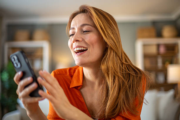 istock Happy woman using smartphone at home, making a video call and laughing 2211788286
