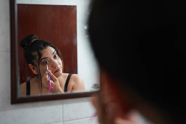 istock Woman applying makeup looking in the mirror in the bathroom 2211793642