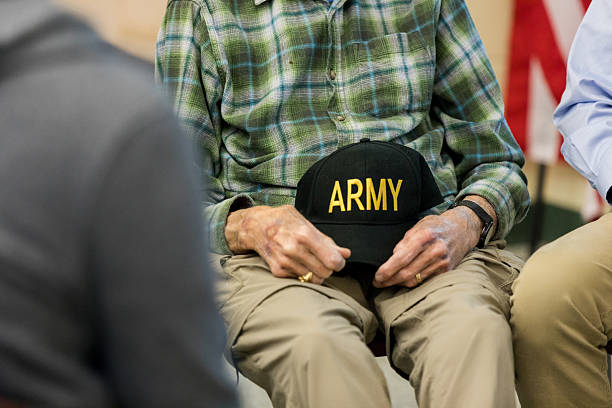 istock Veteran Holding Army Hat in Group Therapy Session 2211795769