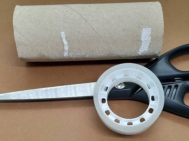 Paint roller and tape standing vertically on yellow background, centered composition with copy space