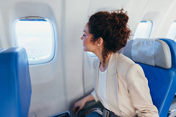 istock Businesswoman looking out the window while flying on an airplane 2211808801