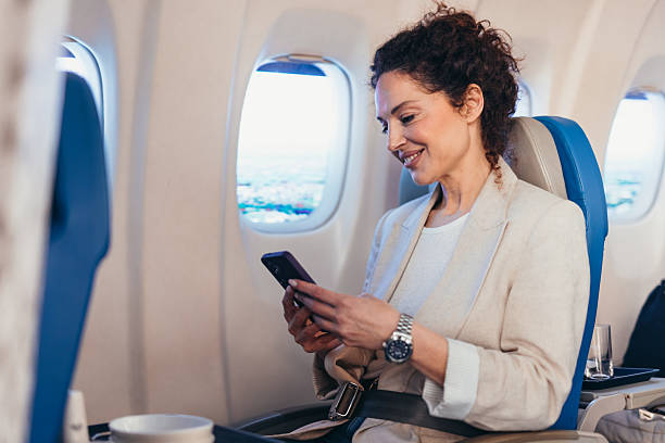 istock Businesswoman using smartphone on airplane near window seat during flight 2211809122