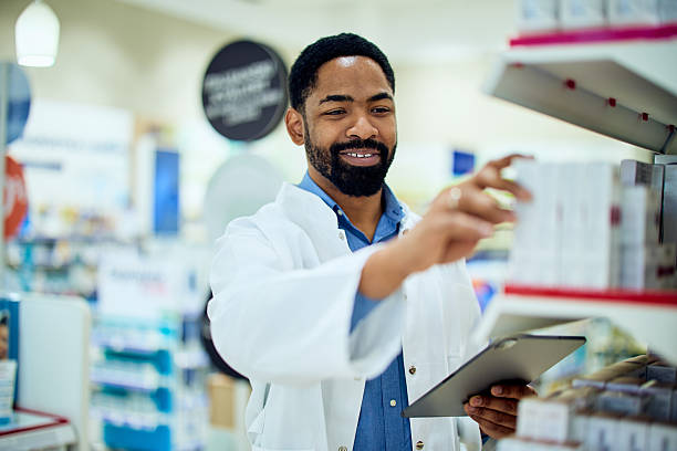 istock Pharmacist Organizing Medicine on Shelf While Holding a Tablet in a Pharmacy 2211810442