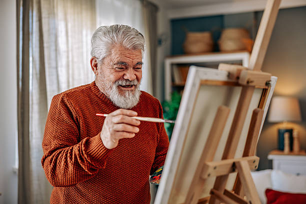 istock Senior Man Painting at Home on a Canvas 2211810477