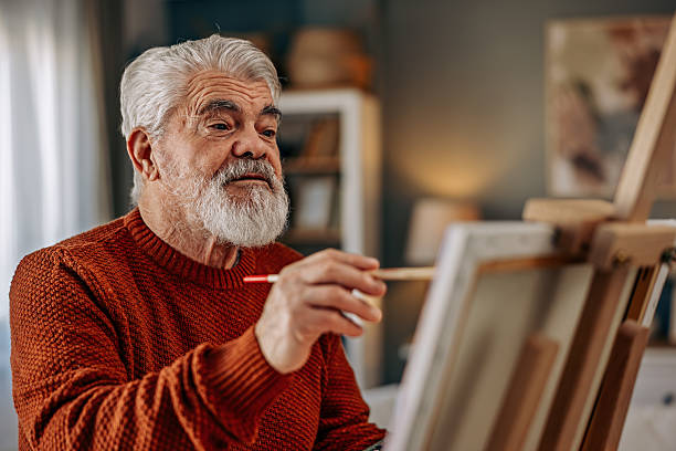 istock Senior Man Painting at Home on a Canvas 2211810492