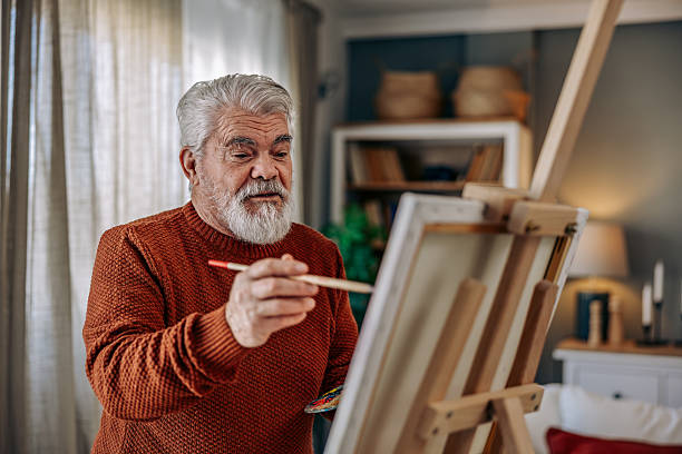 istock Senior Man Painting at Home on a Canvas 2211810504