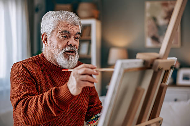 istock Senior Man Painting at Home on a Canvas 2211810506