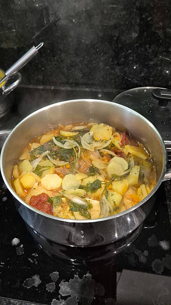 istock Traditional Portuguese codfish stew, known as caldeirada de bacalhau, prepared in a stainless steel pot with sliced potatoes, onions, tomatoes, peppers, herbs and olive oil.Homemade meal on a stovetop 2211810640