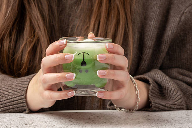 Woman holding a bear shaped glass with matcha latte