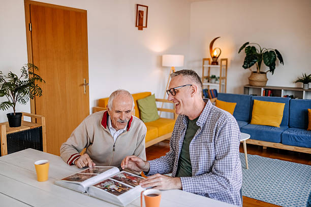 istock Enjoying talking with older people at home while sitting on dining table and looking at photo album 2211826389