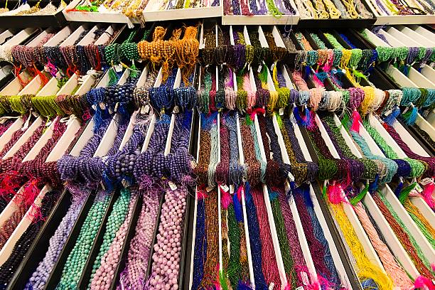 istock Multi-colored stone strands hang in grouped bundles on a tiered table, their facets glinting in the display light. 2211826564