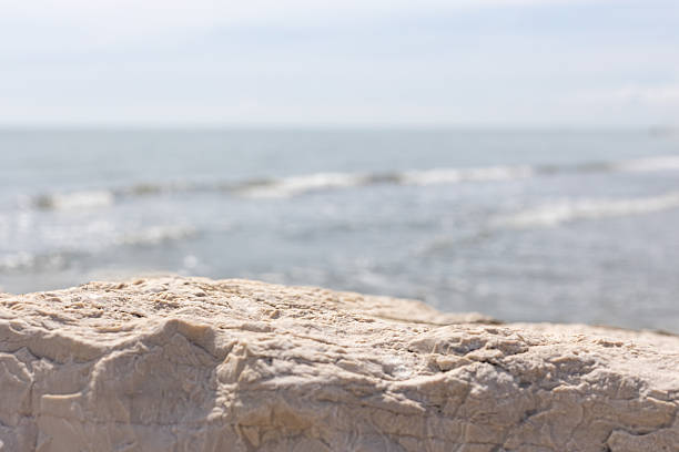 Detailed foreground rock with visible cracks and sea waves in soft background perfect for product display or design mockup.