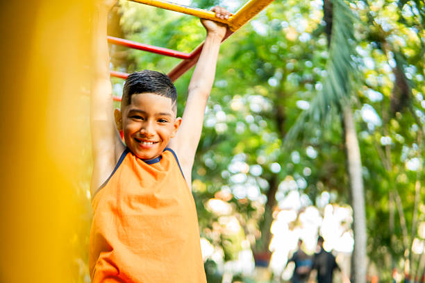 Portrait of a cheerful elementary age boy having fun on playground equipment in a park