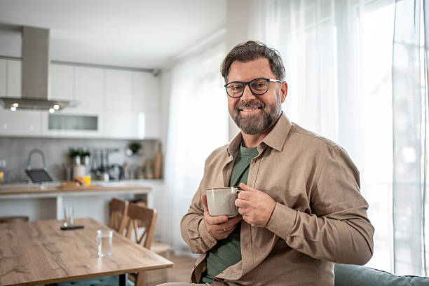 istock Mid adult man smiling and holding a mug in his modern kitchen 2211833046