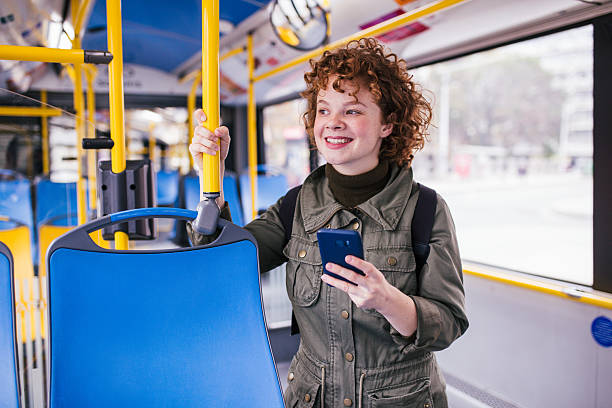 istock Young woman standing on bus using smartphone 2211835557