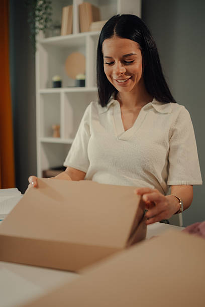 istock Young entrepreneur opening a package in her home office 2211835917