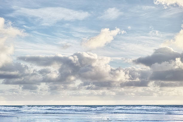 A serene seaside scene featuring a vast expanse of ocean beneath a dramatic sky filled with clouds. The tranquil waves lap gently against the shore, evoking peace and appreciation for nature's beauty.
