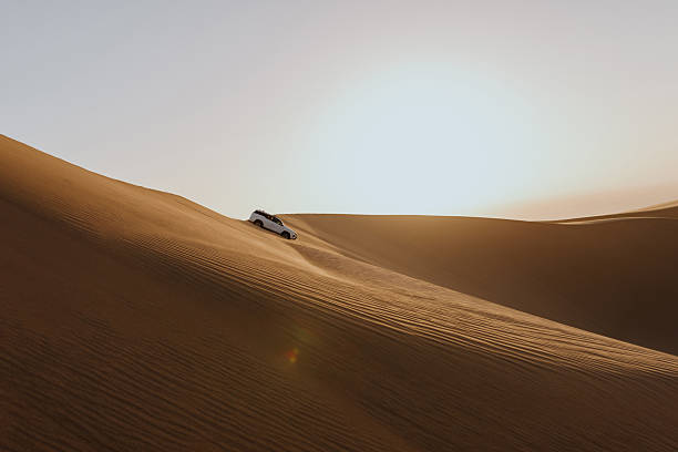 istock White suv car climbing up sand dune in desert at sunset 2211844426