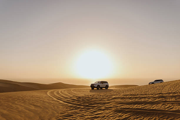 istock Two off-road vehicles exploring the desert dunes at sunset 2211844427