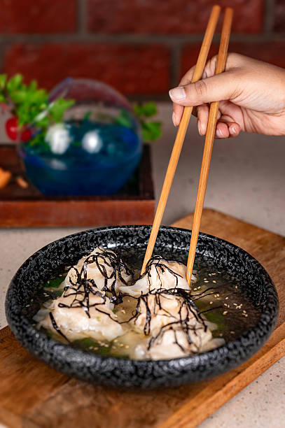 Asian Dumplings in Clear Broth with Seaweed – Hand Using Chopsticks