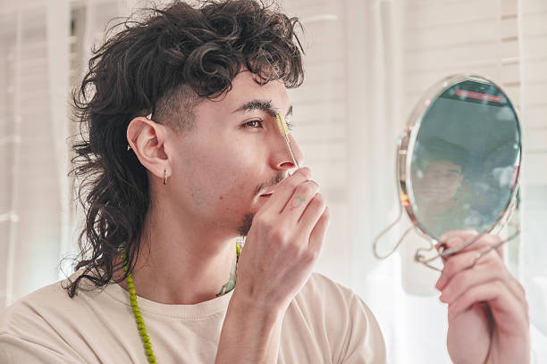 istock Young man waxing eyebrows with mirror at home 2211847955