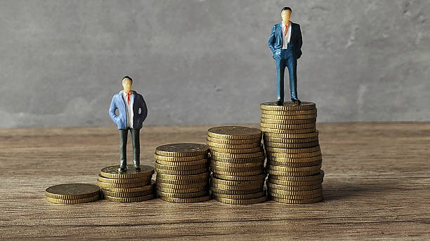 istock Miniature businessman or professional standing on ascending gold coins stack. 2211869427