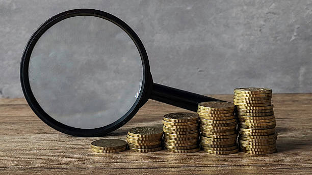 istock ascending gold coins stack together with magnifying glass on wooden table 2211869436