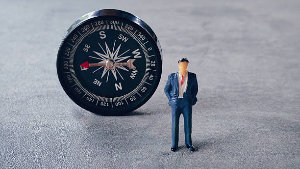 istock Miniature businessman and a compass 2211869528