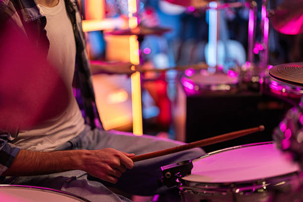istock Young man playing drums during rehearsal in neon lit studio 2211869840