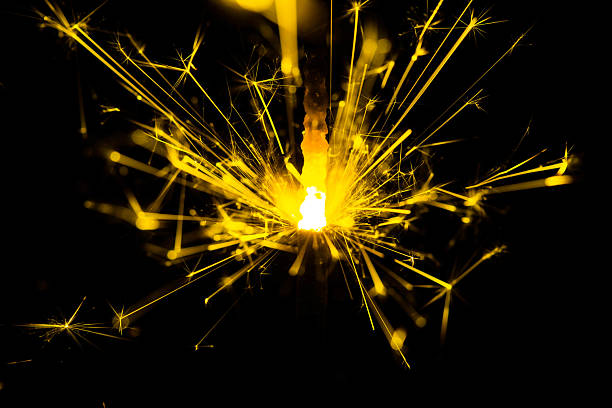istock Bright Sparkler Flame Igniting Celebration with Bright Yellow Sparks Against Black Background 2211875110