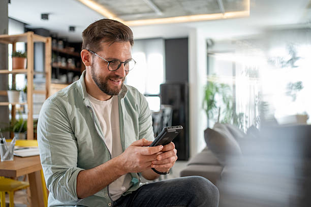 istock Young man using smartphone at home: enjoying mobile technology 2211879279