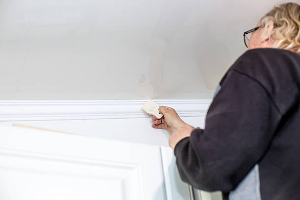 istock A man uses a rubber spatula to fill the joints on the ceiling after installing skirting boards. Home renovation 2211881219