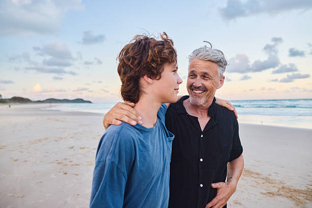 istock Father and son walking on the beach at sunset in australia 2211885000
