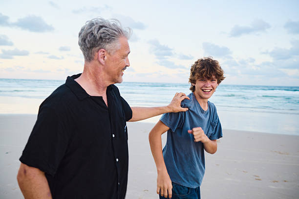 istock Father and son walking on the beach at sunset in australia 2211885010
