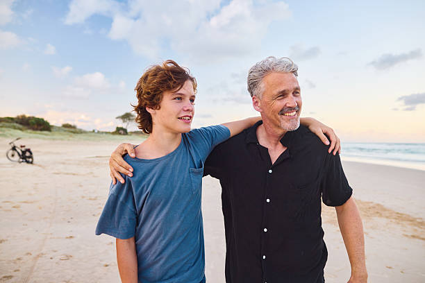istock Father and son walking on the beach at sunset in australia 2211885011