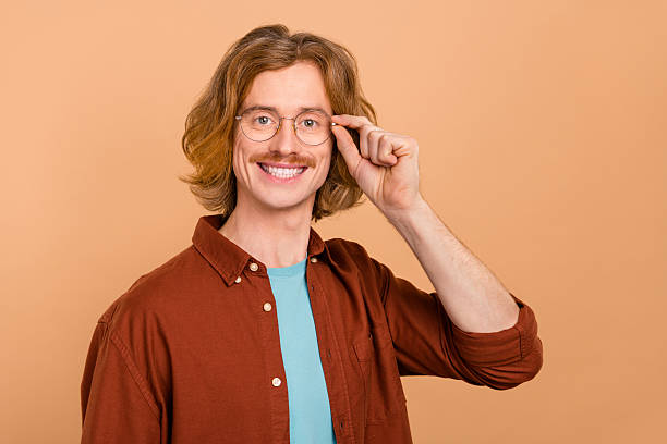 istock Portrait of attractive intelligent cheerful red-haired guy touching specs isolate over beige pastel color background 2211888329