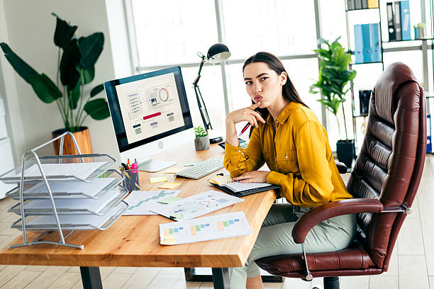 istock Skilled professional businesswoman working in a modern office setting, looking thoughtful while analyzing charts and data on her compute 2211889936
