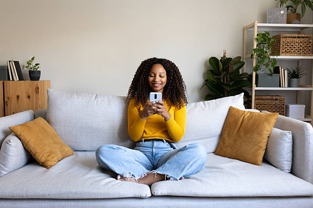 istock Young woman using smartphone and relaxing on sofa at home 2211890333