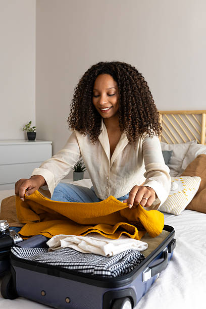 istock Young woman packing clothes into suitcase on bed 2211890347