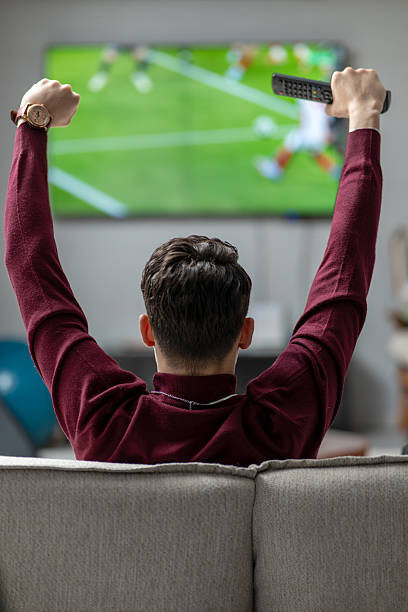 istock Man watching a soccer match on TV at home 2211892159