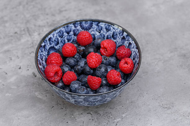 Berries in a bowl, blueberries and raspberries closeup isolated fruits in ceramic bowl