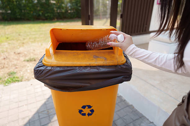 istock Recycling and Waste Disposal Practices. A woman recycling plastic bottles at a designated bin. 2211892878