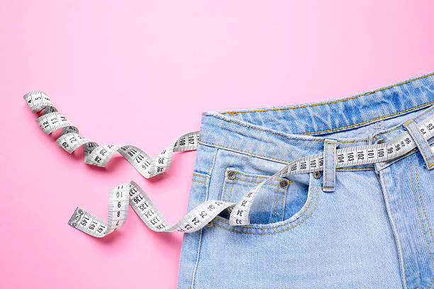 istock Jeans and measuring tape on pink background, top view 2211892926