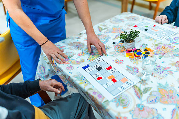 istock Nurse assisting elderly man playing bingo in nursing home 2211892934