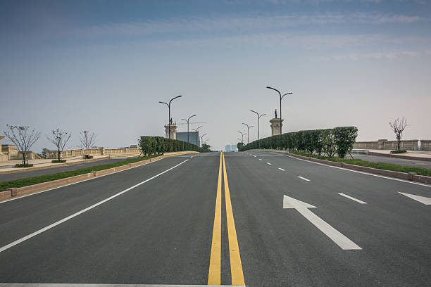 istock Serene Urban Roadway Surrounded by Lush Greenery and Architecturally Styled Light Poles 2211893064