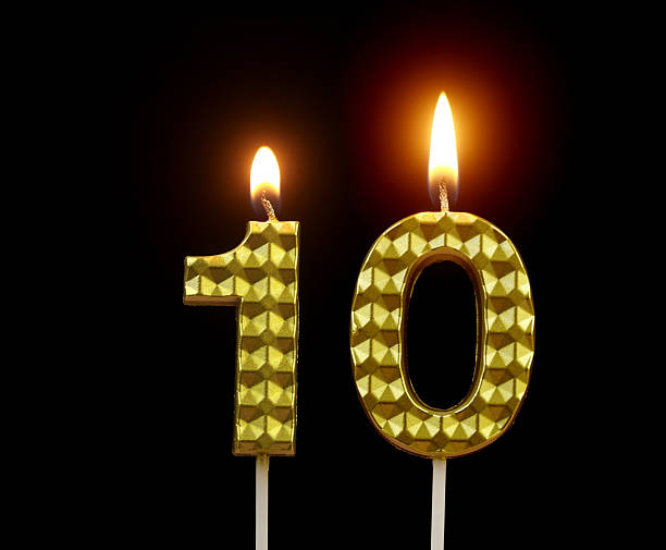 istock Gold birthday candles burning on black, number 10. 2211893951