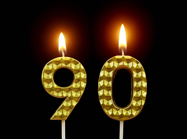 istock Gold birthday candles burning on black, number 90. 2211893979